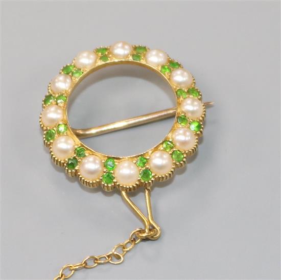 An Edwardian yellow metal, demantoid garnet and seed pearl circular open work brooch, with safety chain, 20mm.